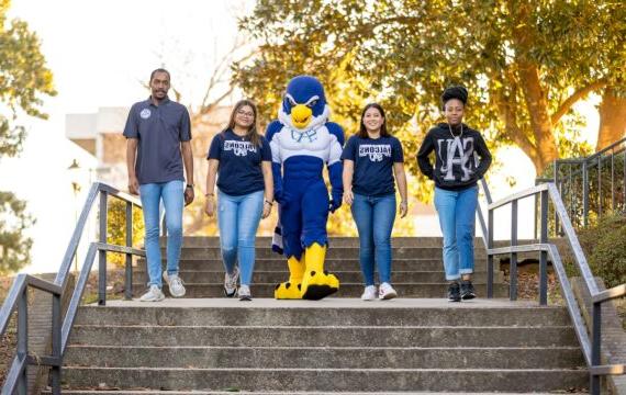 Four students walking down the outdoor steps with Auggie the mascot